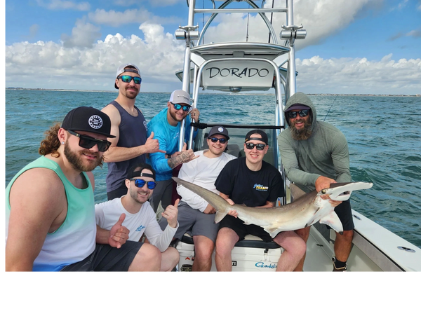 clients with a hammerhead they caught while on a shark fishing charter