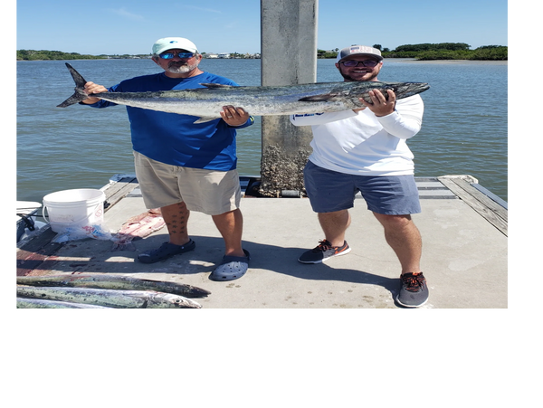clients holding a kingfish while on a deep sea fishing trip