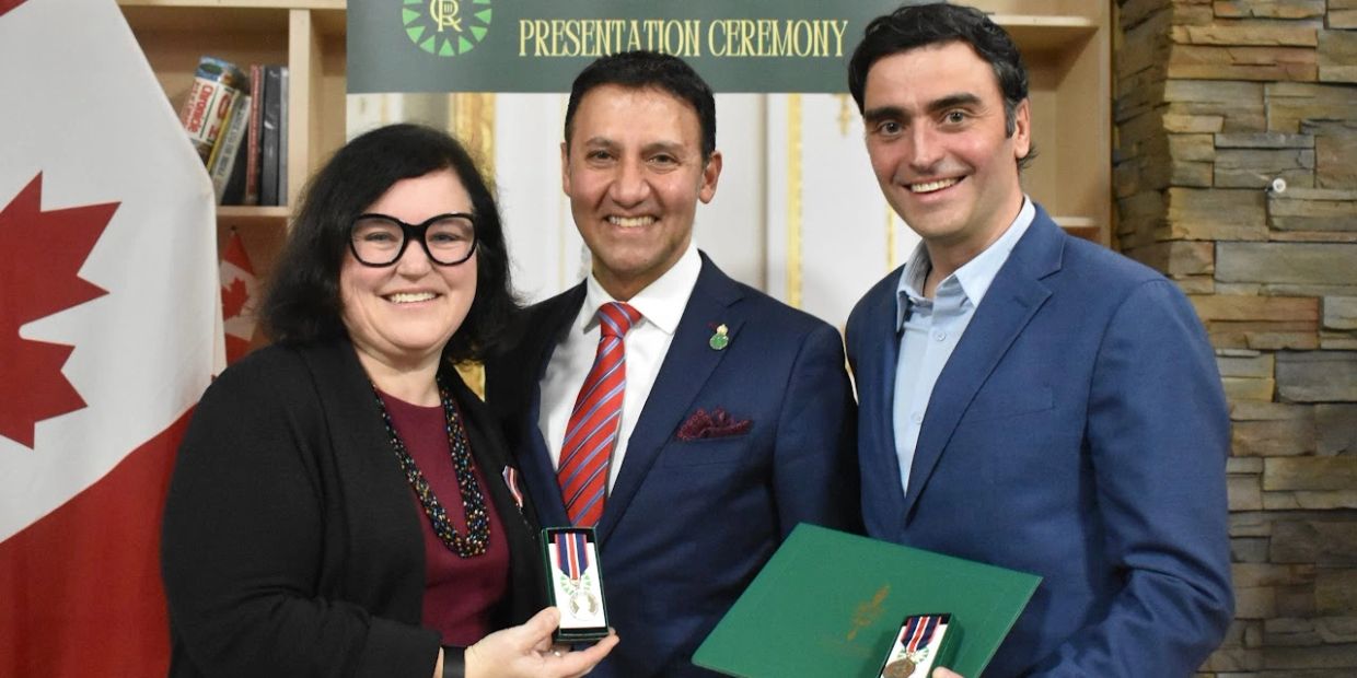 Three people smiling at a presentation ceremony with medals.