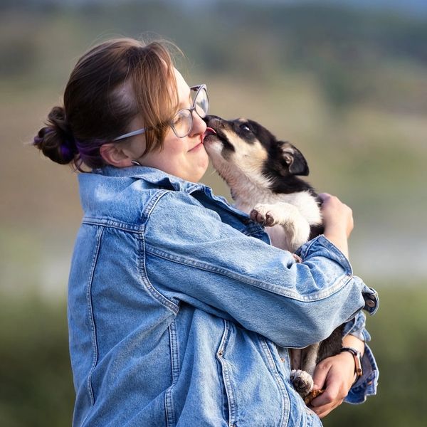 Woman getting kissed by a small dog