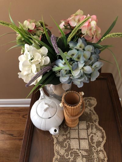 tea set with a white vase full of flowers