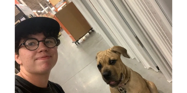 A man and a boxer puppy practice obedience in a hardware store.