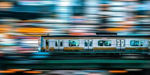 A train speeding through a cityscape with vibrant, blurred lights. Talent Acquisition as a Service | RPO | Embedded Recruitment Solutions | Executive Search | Japan