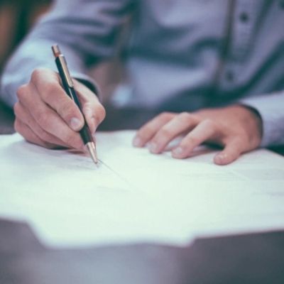 An unknown man writing on documents that can't be made out from the blur with a pen.