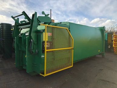 Green waste compactor with yellow guard for commercial waste and recycling.