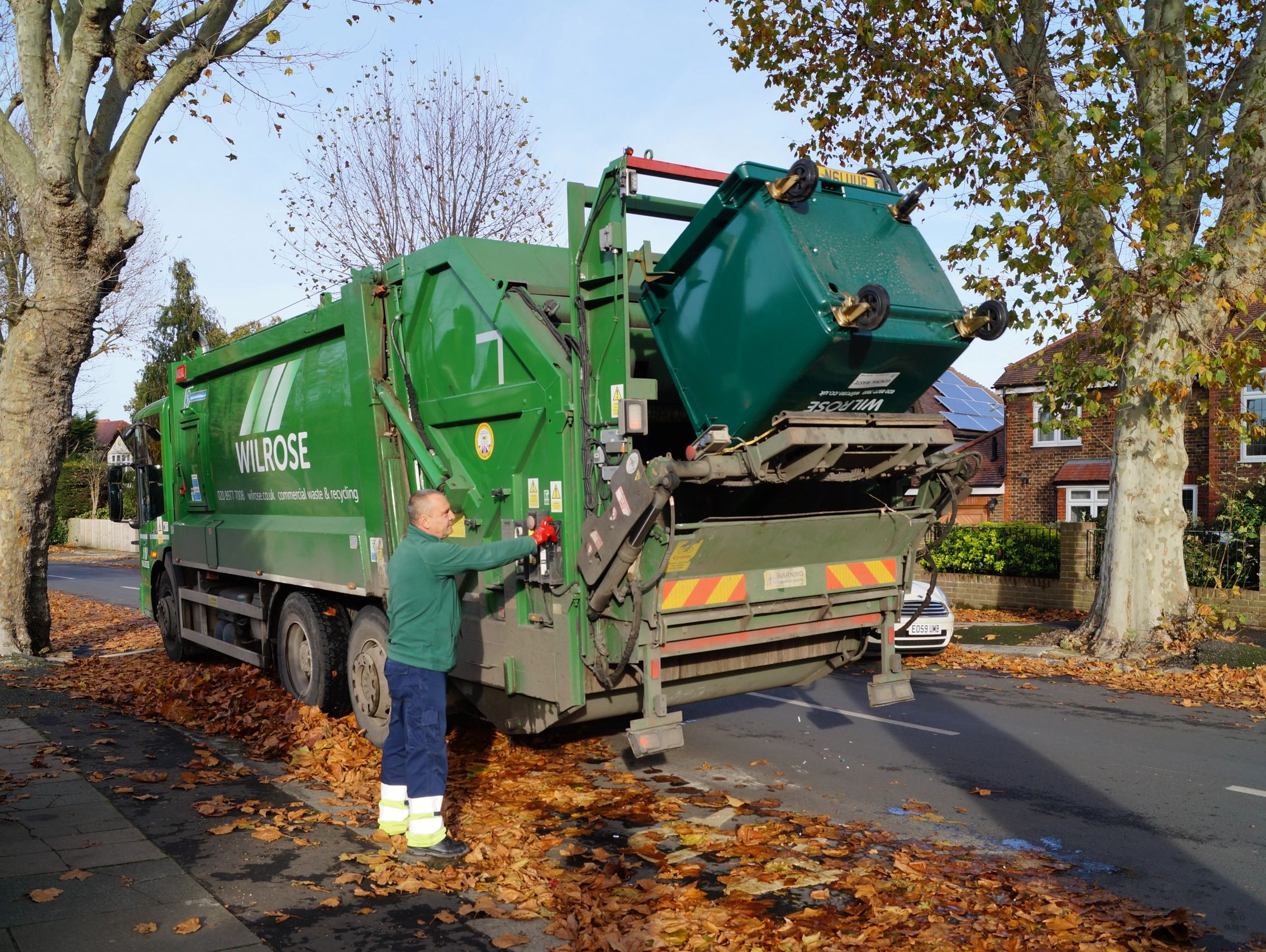 Dustcart driver tipping an 1100 litre wilrose wheelie bin