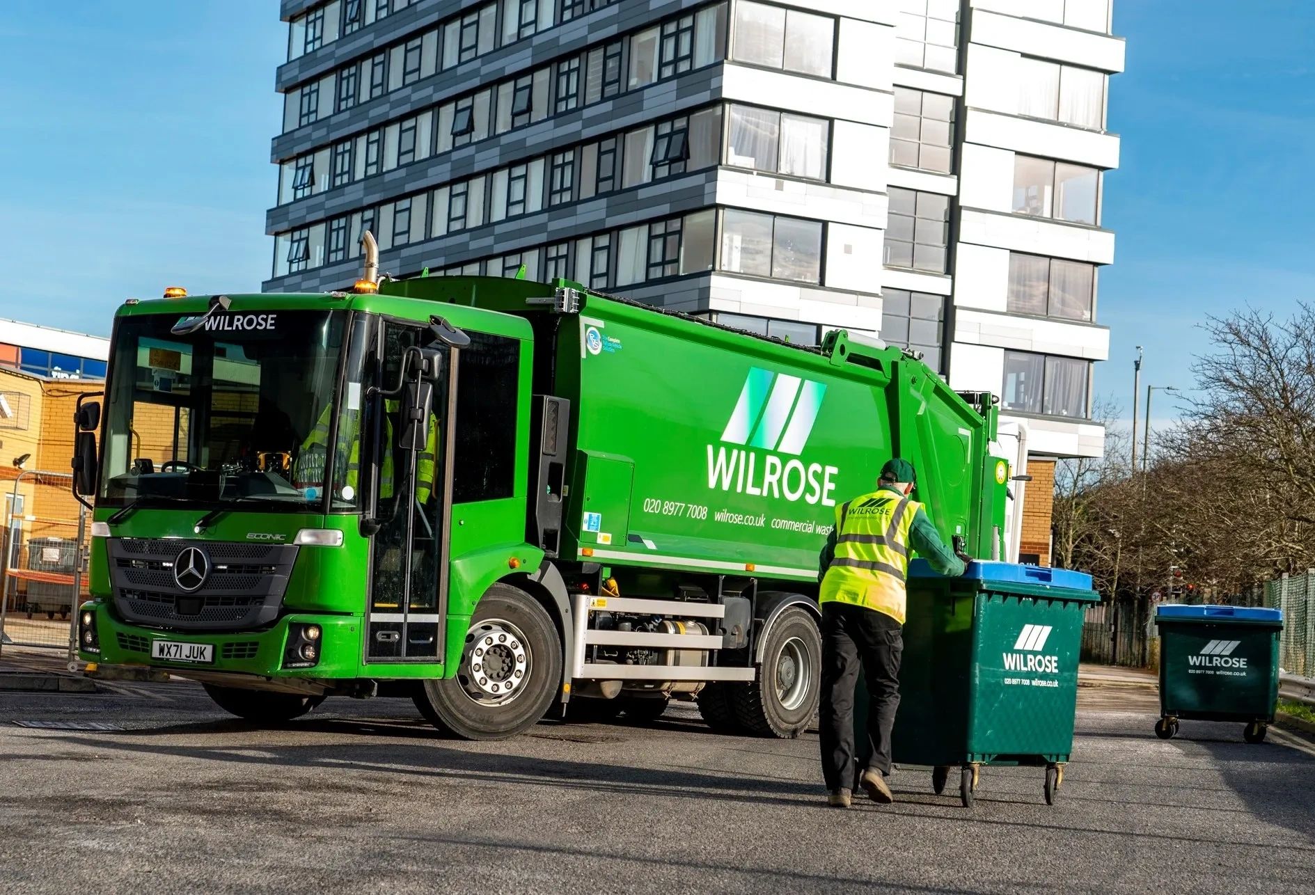 Driver wheeling Wilrose bin towards a Wilrose dustcart.