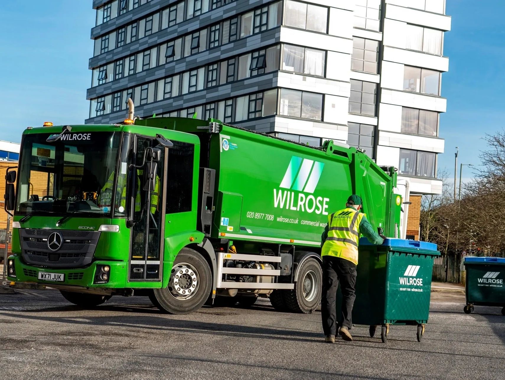 Driver wheeling Wilrose bin towards a Wilrose dustcart.