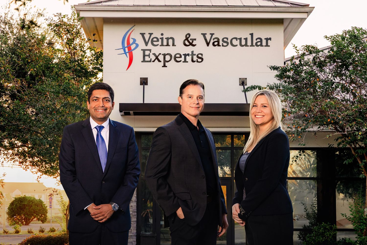 Three professionals standing outside Vein & Vascular Experts building.