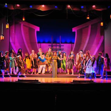 A colorful stage musical performance with a large cast.