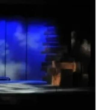 Dimly lit stage with blue backdrop and seating.