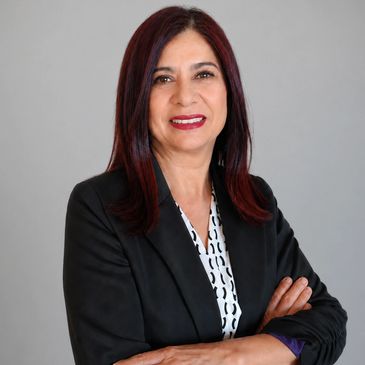 Confident woman in a black blazer with arms crossed, smiling at the camera.