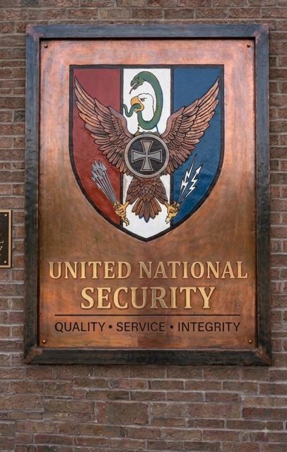 United National Security sign with eagle emblem on brick wall.