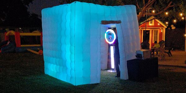 Glowing inflatable photo booth at night in a backyard party.