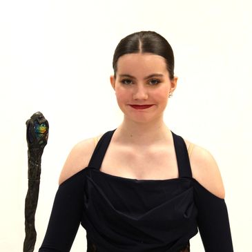 Young woman in black dress holding a staff with a carved top.