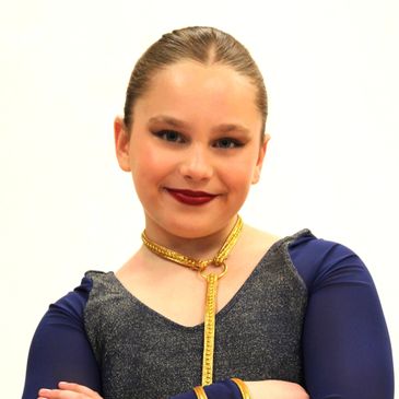 Young girl in a blue and glittery costume with confident smile.