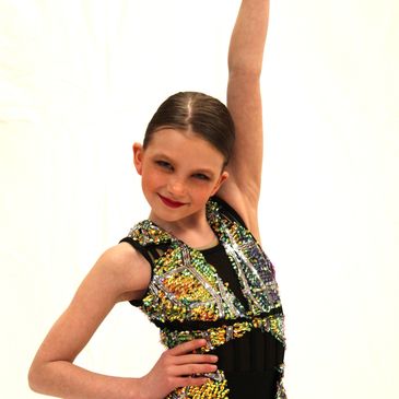 Young girl in a sparkling dance costume striking a confident pose.