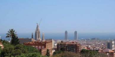 Cityscape view with modern towers and a church under construction by the sea.