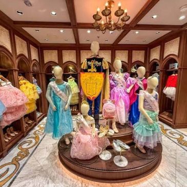 Display of colorful princess dresses and accessories on mannequins in a boutique.