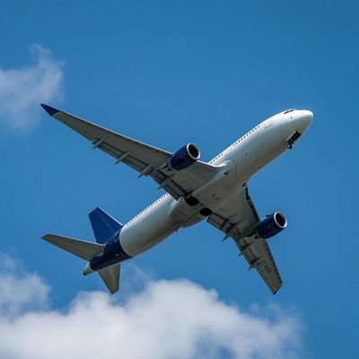 Commercial airplane flying against a clear blue sky with some clouds.