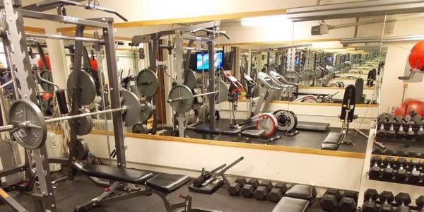 A well-equipped gym with various weights and machines.