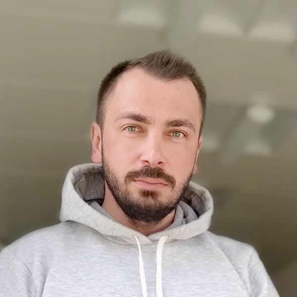 Man with a beard wearing a gray hoodie looking at the camera.