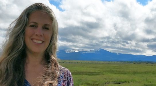 Female business owner standing in front of mountain range.