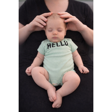 A baby peacefully sleeping while being gently held and supported by an adult.