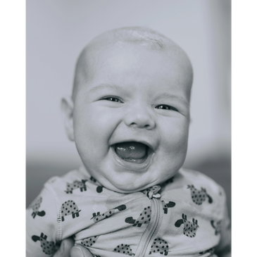 Close-up of a joyful baby laughing with wide open mouth.