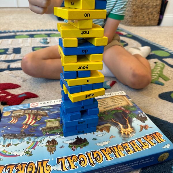 A child playing Jenga with blue and yellow blocks.
