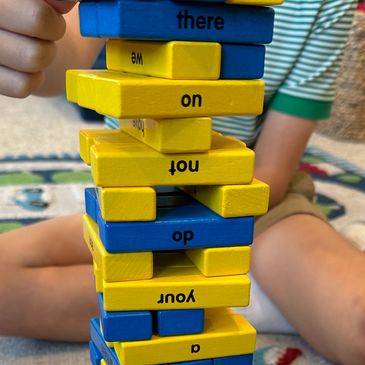 A child playing Jenga with blue and yellow blocks.