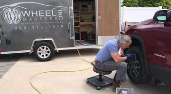 Wheel technician sands down a damaged alloy rim on a GMG Acadia for Light House Buick in Morton, IL.