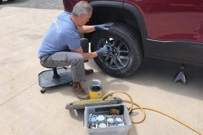 Wheel repair specialist cleans the repaired wheel on a  2020 GMC Acadia before painting it. 