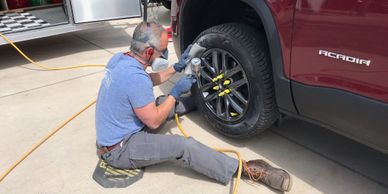 Wheel repair tech sprays a 2018 GMC Acadia rim. 