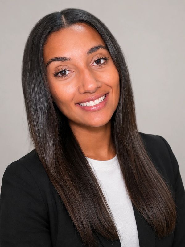 Smiling woman with long straight hair in business attire against a neutral background.