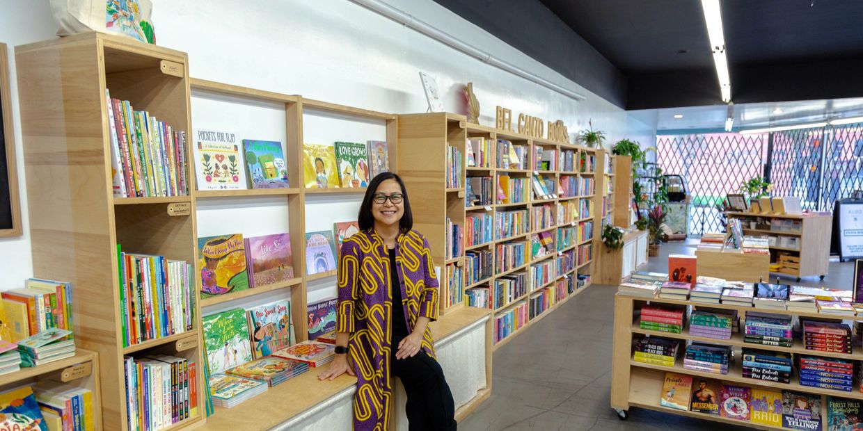 Bel Canto Books owner, Jhoanna Belfer, sitting in front of bookshelves at KUBO LB.