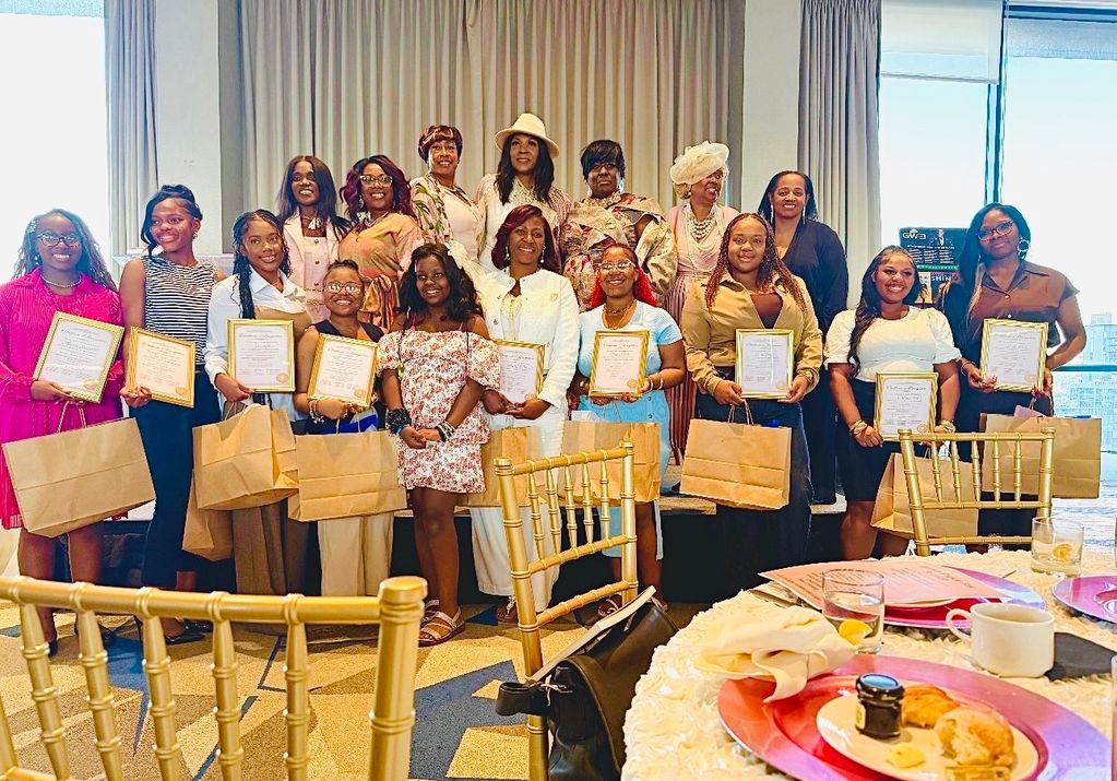 Group of women holding certificates and gift bags at a celebratory event.