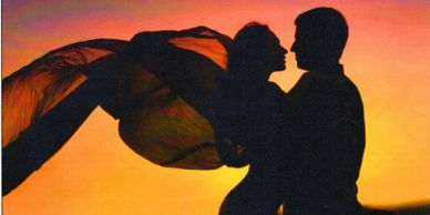 Silhouetted couple embracing at sunset with flowing fabric.