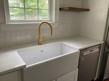 Modern kitchen sink with gold faucet and white countertop.
