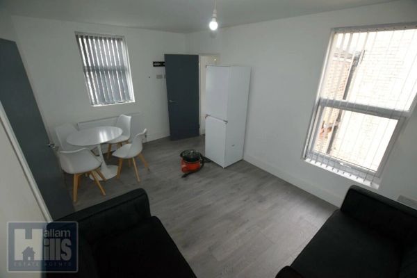 Minimalist room with black sofas, round table, and fridge.