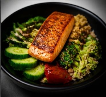 Grilled salmon with cucumber, broccoli, quinoa, and tomato in a black bowl.