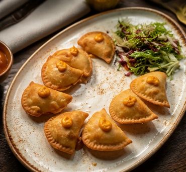Plate of fried empanadas with a dollop of sauce and a side of salad.