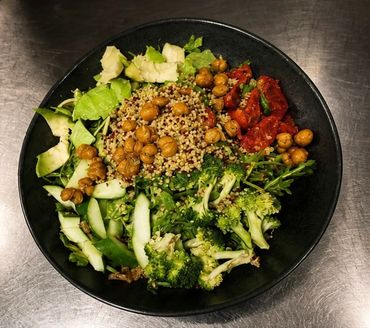 Healthy bowl with broccoli, quinoa, chickpeas, sun-dried tomatoes, and fresh greens.