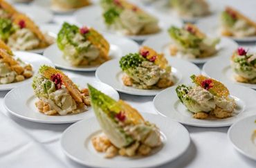 Plated gourmet appetizers with creamy topping and garnishes on a white table.
