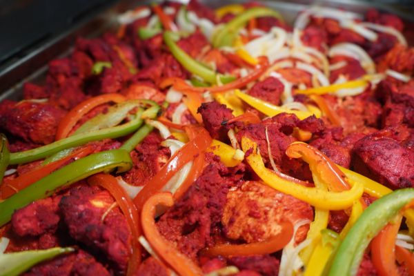 Close-up of spicy grilled chicken with bell peppers and onions.