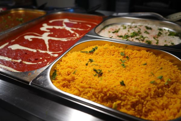 Trays of Indian dishes including yellow rice and curry.