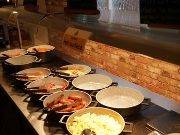 Buffet with multiple pans of food and hot surface sign.