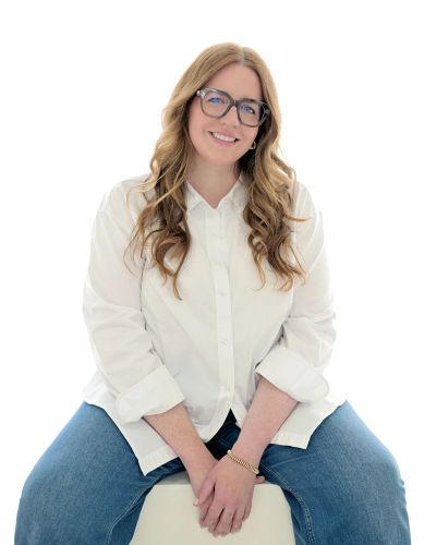 Femme souriante vêtue d'une chemise blanche et lunettes.