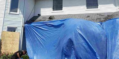 Tarps protecting house from shingle debris