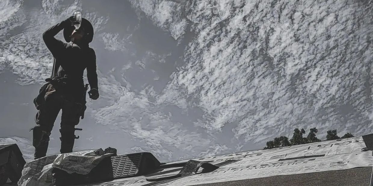 Ngr roofer drinking water on a roof in kitchener